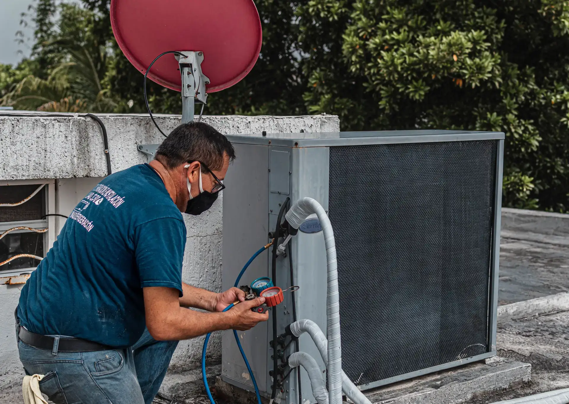 A Summit technician charging a home air-conditioning condenser with a refrigerant manifold gauge