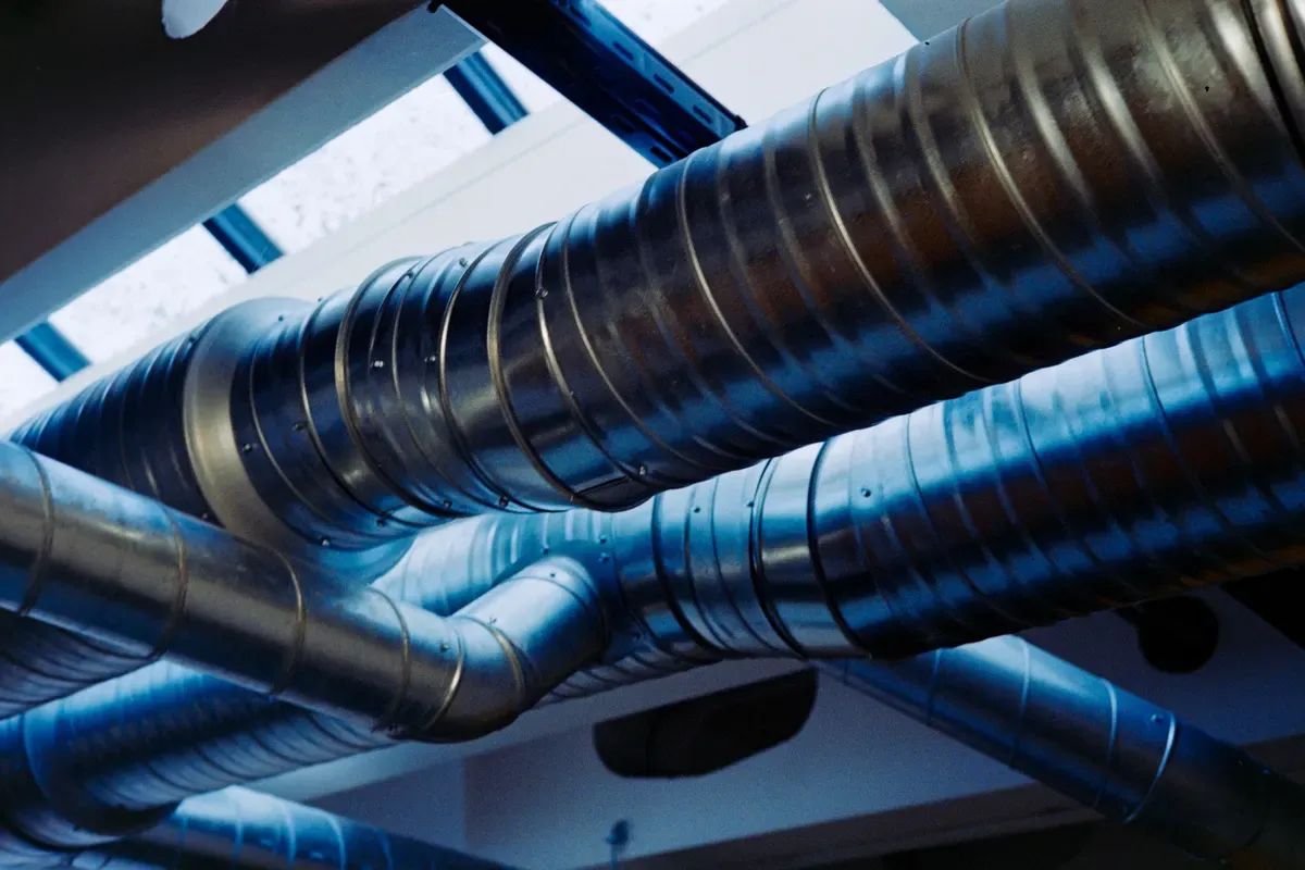 Spiral sheet-metal supply ducts running along a ceiling