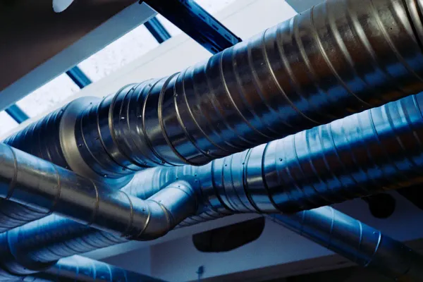Spiral sheet-metal supply ducts running along a ceiling